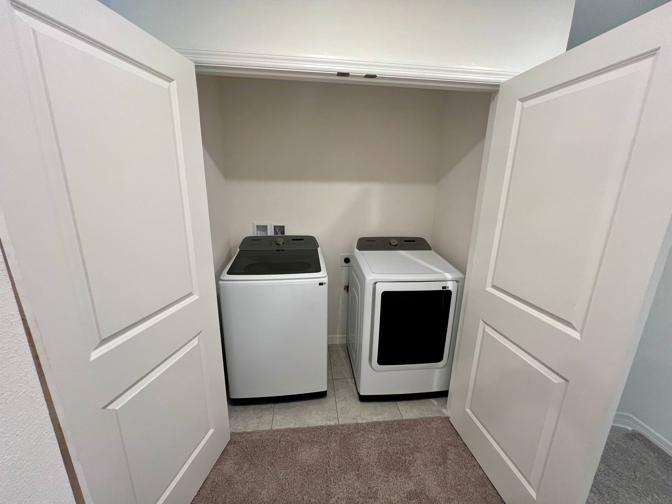 Compact laundry area with an open-door closet showcasing a modern washer and dryer set.