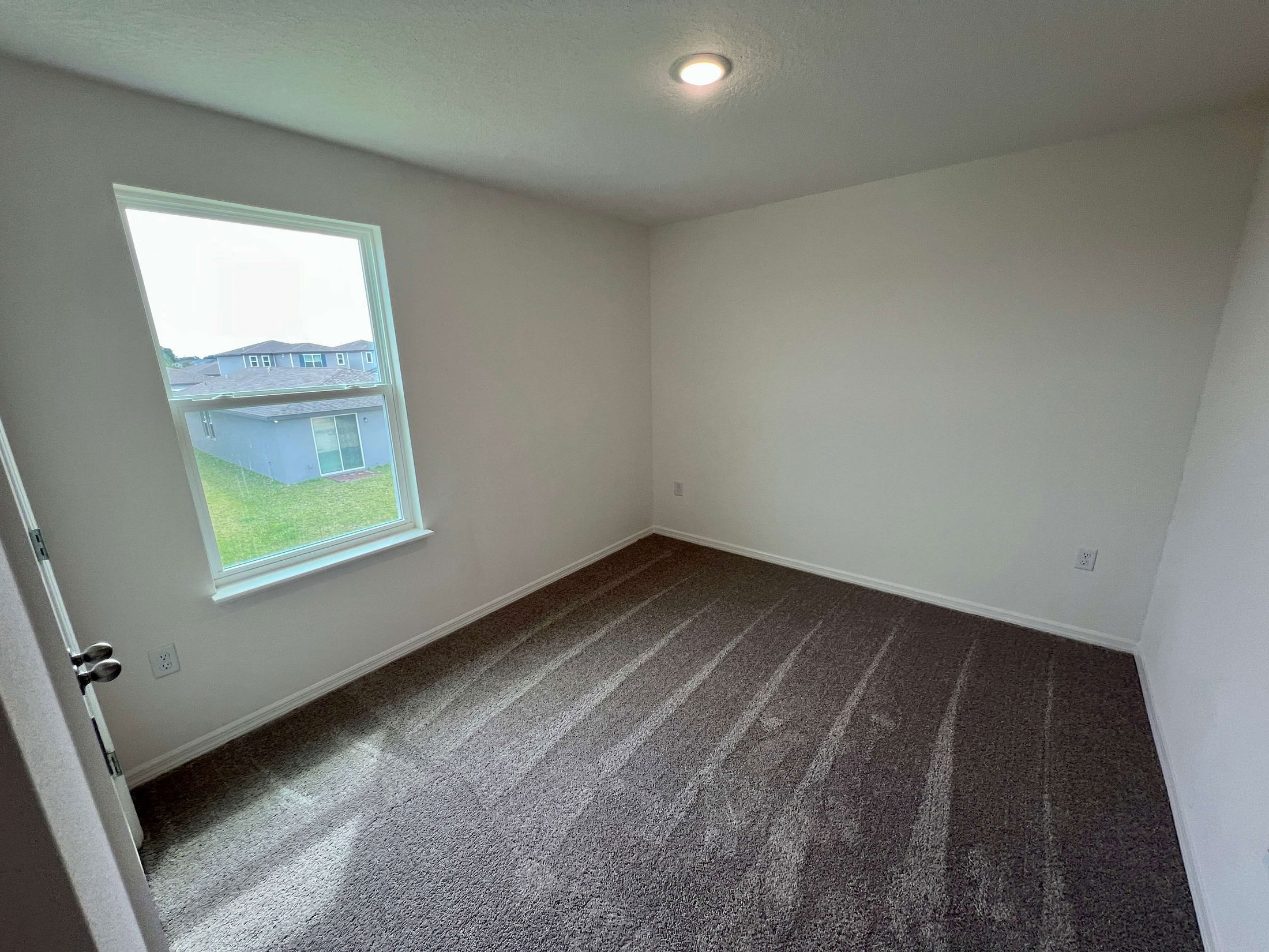 Empty room with clean carpet and a window offering natural light.