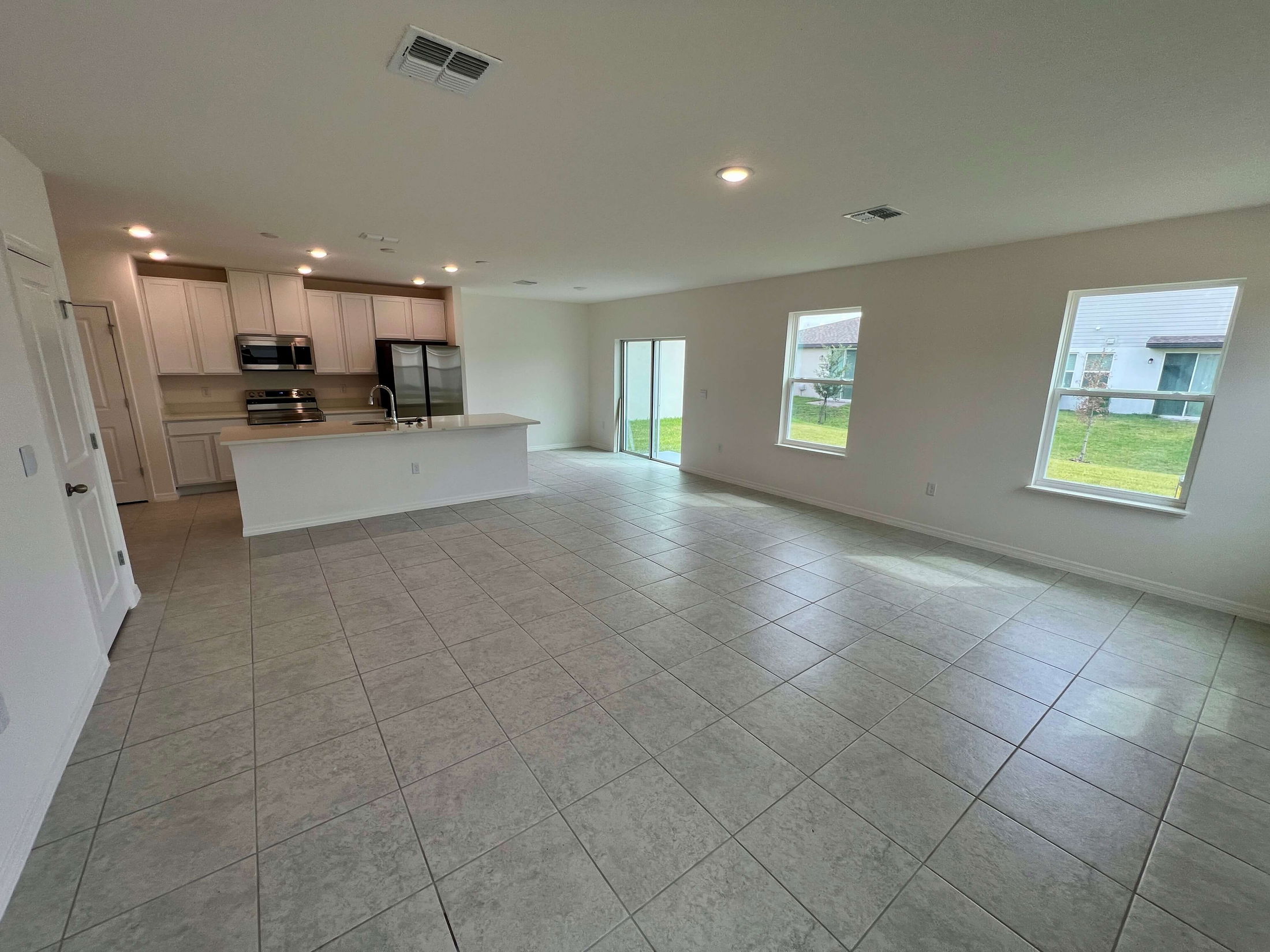 Spacious open-concept kitchen and living area with tile flooring and large windows offering a bright, airy atmosphere.