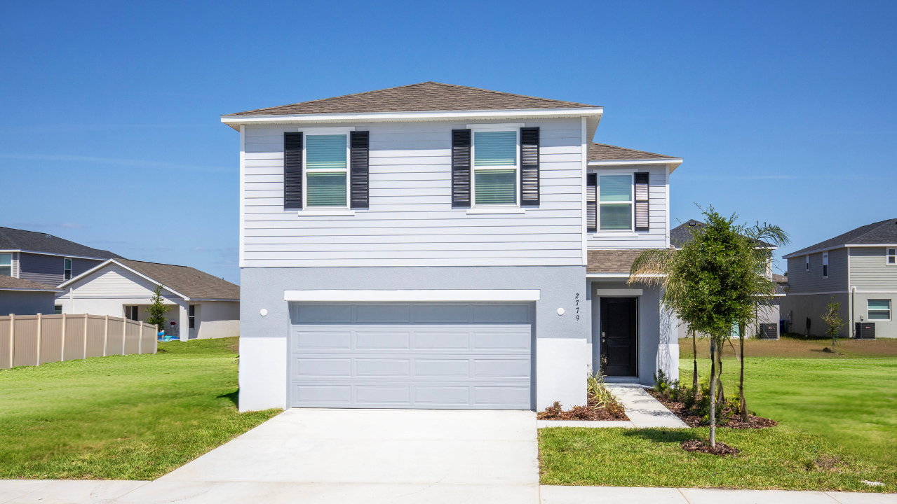 Modern two-story suburban home with a gray facade, attached garage, and neatly landscaped front yard under a clear blue sky.