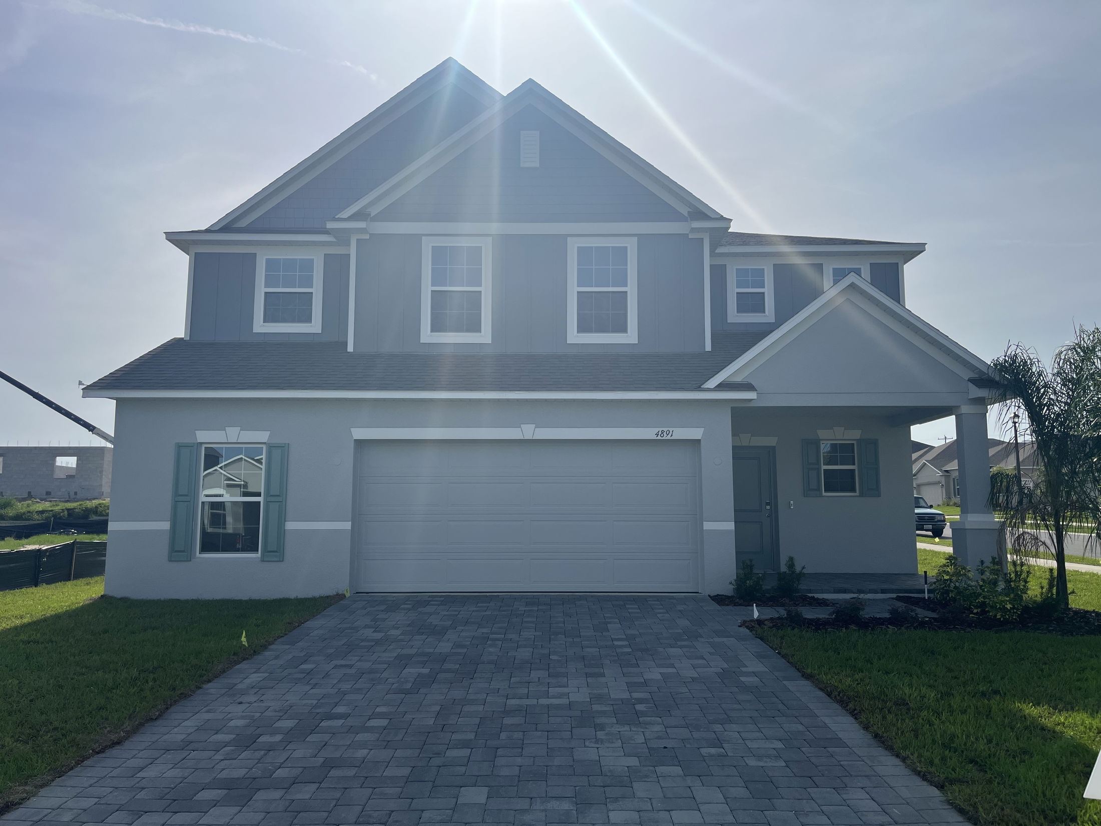 Two-story suburban house with a gray facade, wide driveway, and a neatly maintained front lawn.