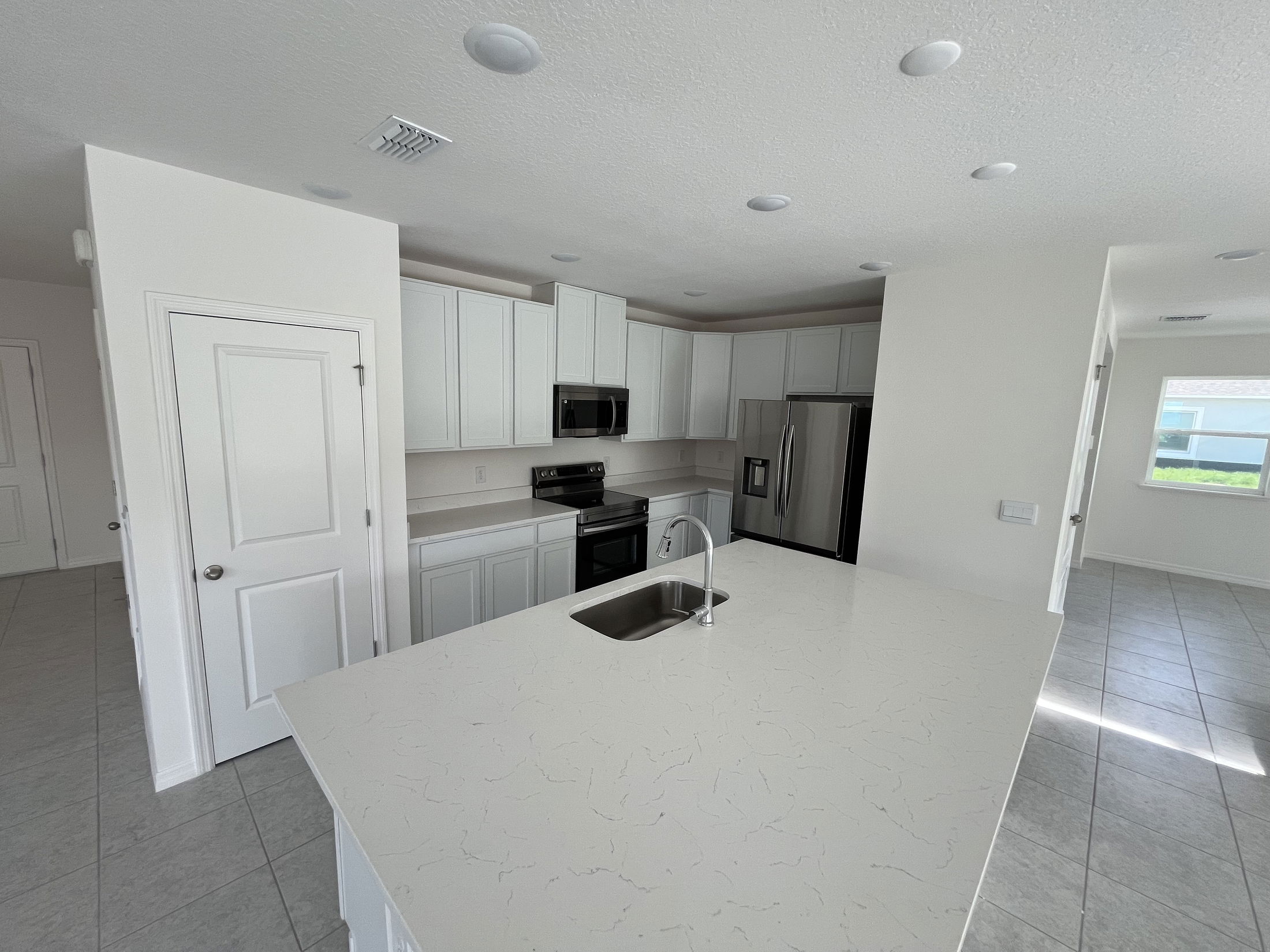 Modern kitchen with white cabinets, stainless steel appliances, and a large island featuring a built-in sink.