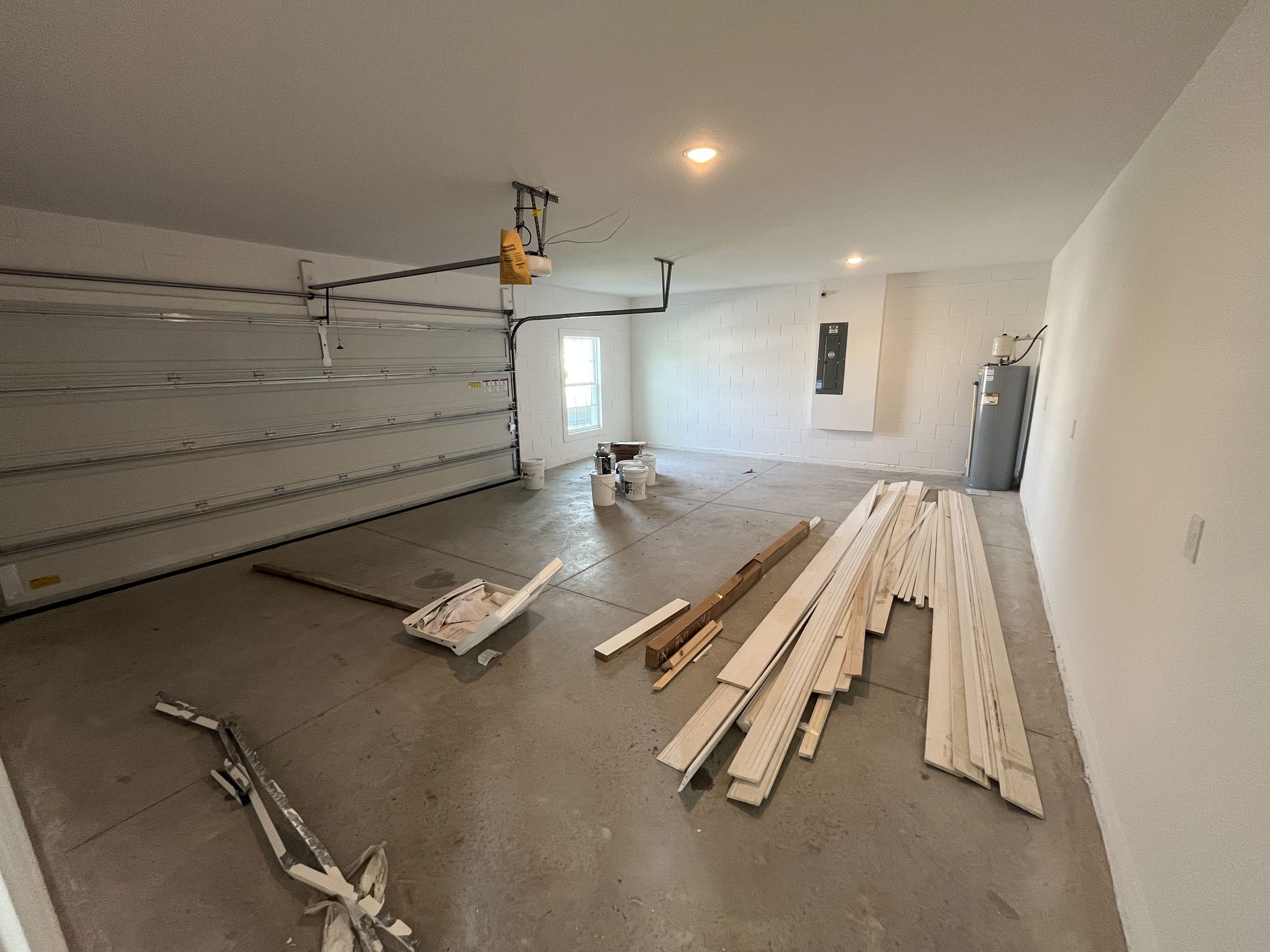 Spacious garage interior with construction materials and a water heater.