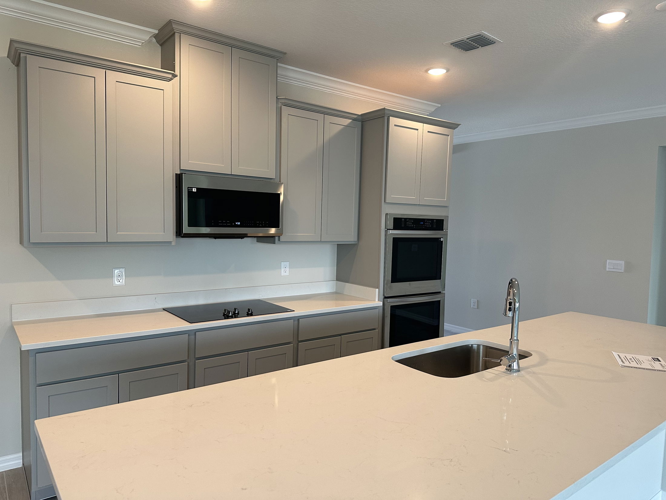 Modern kitchen with sleek gray cabinets, stainless steel appliances, and a large island featuring a built-in sink.