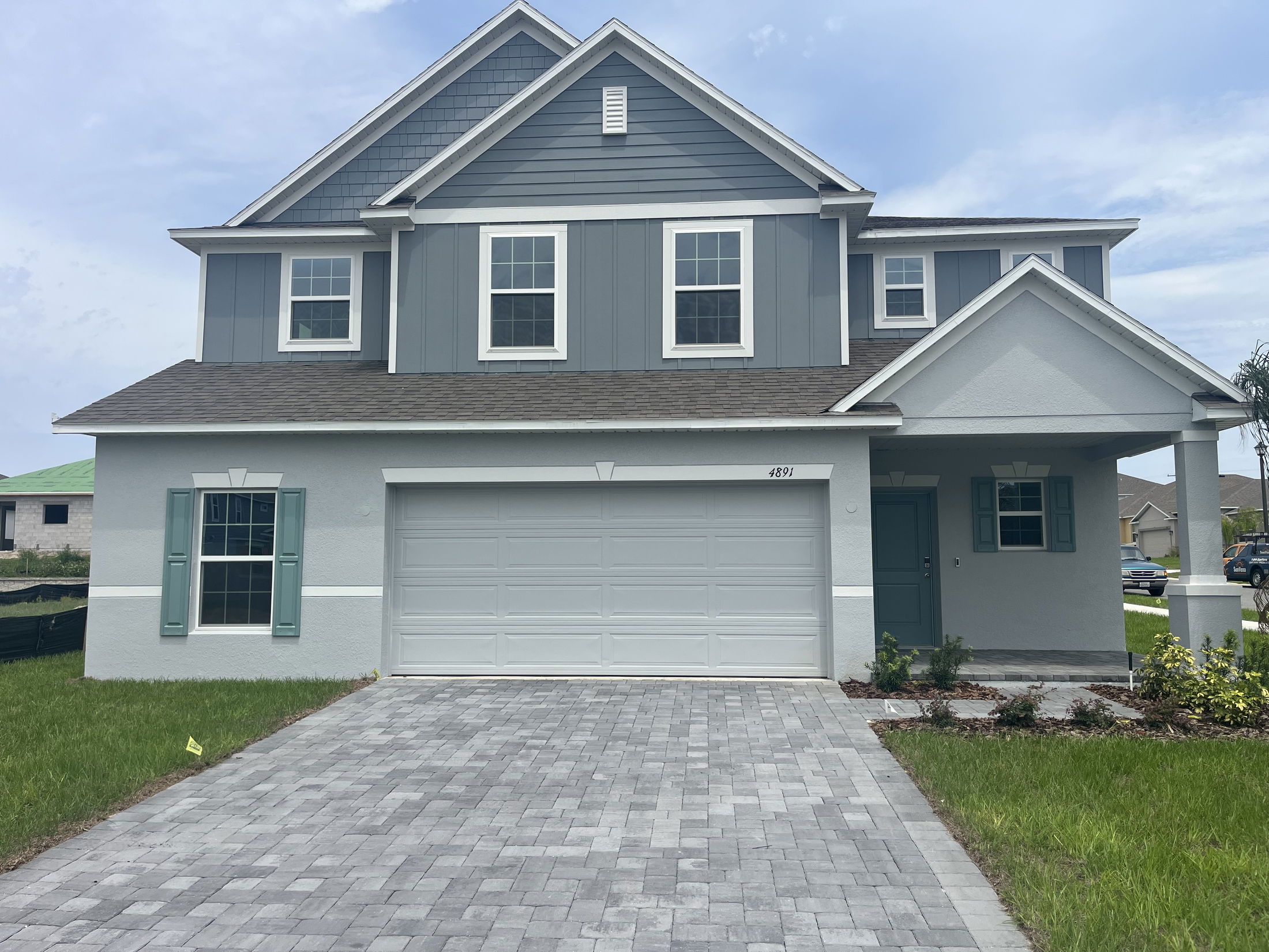 Modern two-story blue and gray house with a double garage and paved driveway.