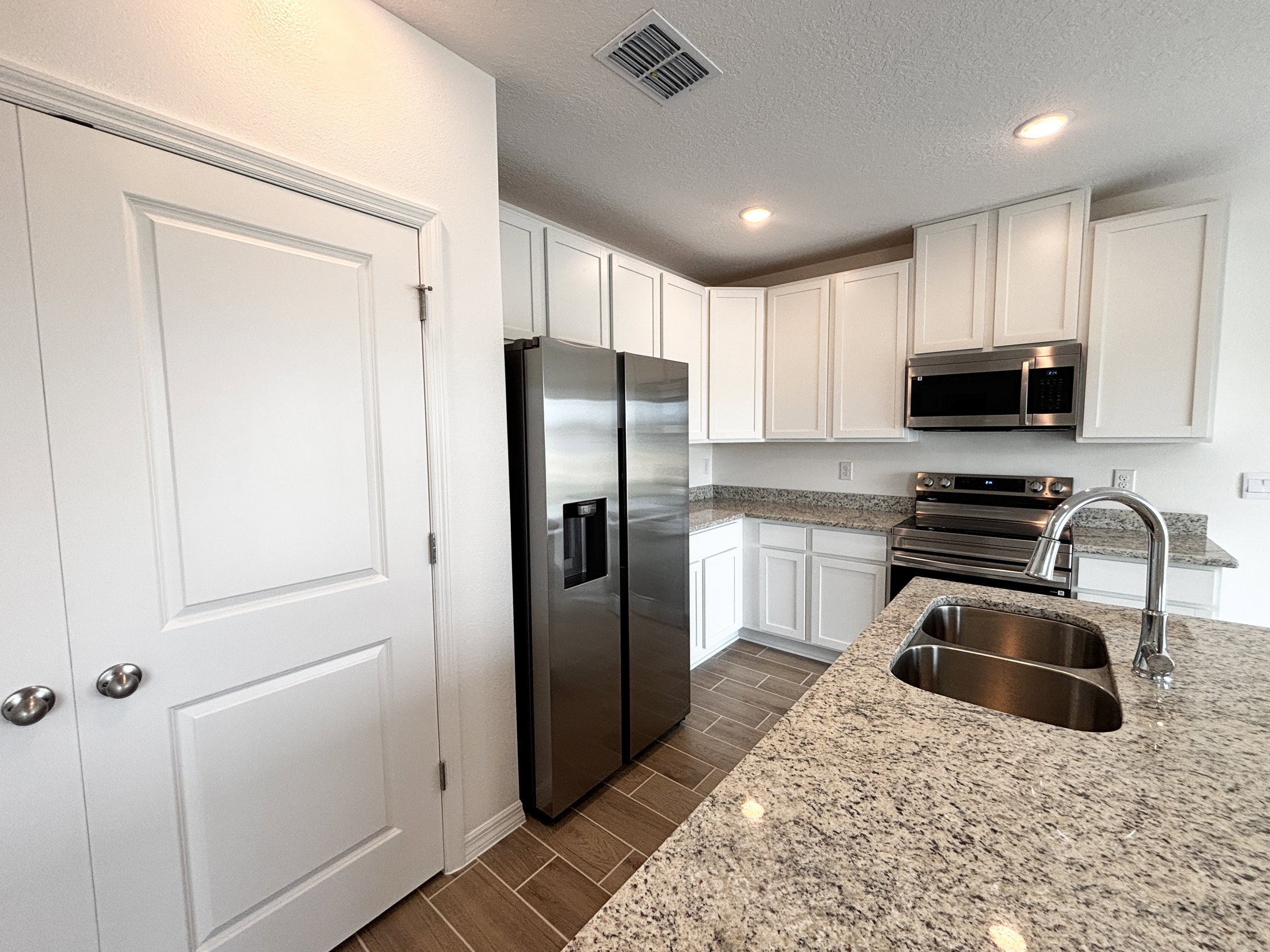 Modern kitchen featuring stainless steel appliances, white cabinets, and granite countertops.