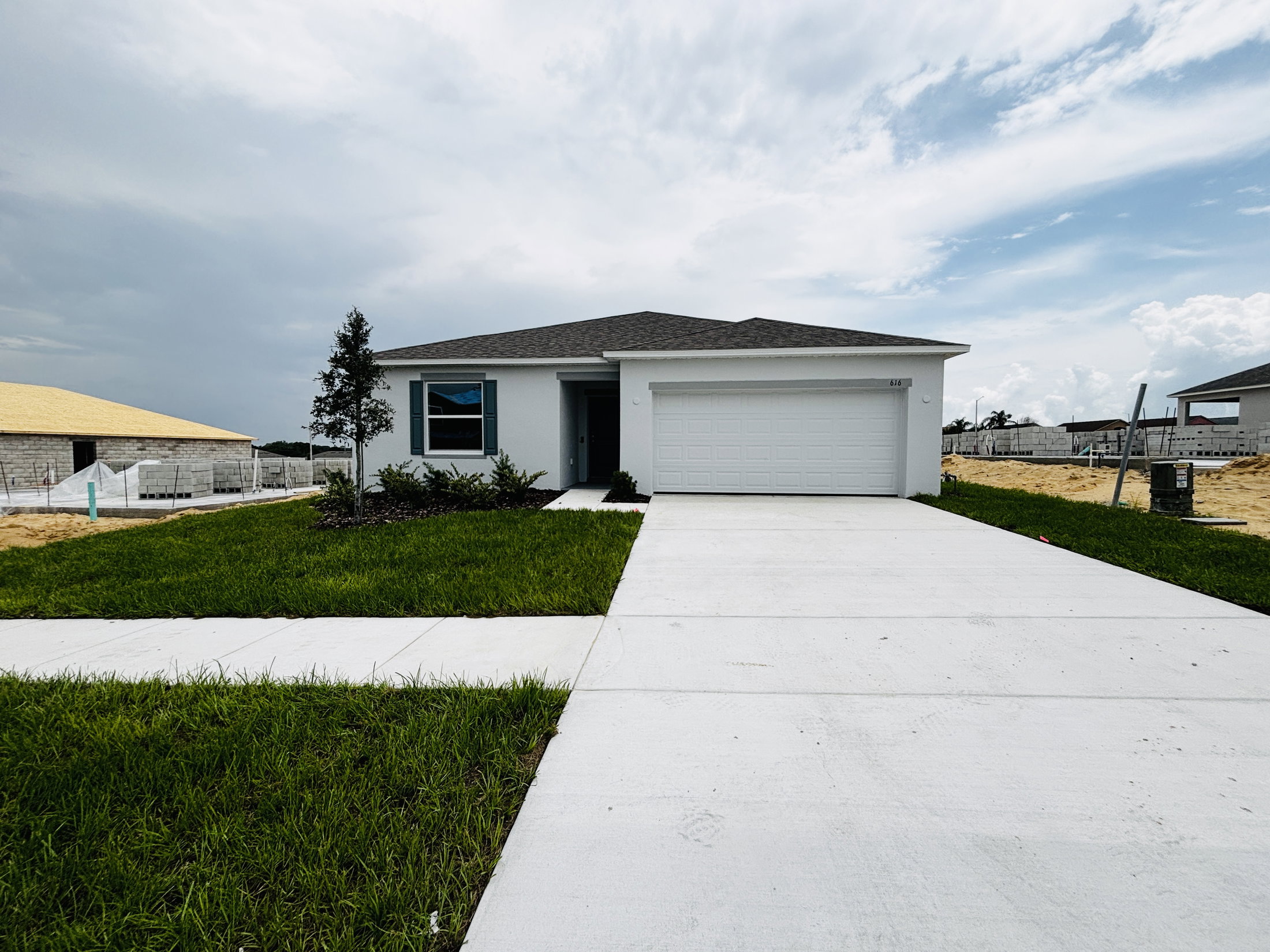 Single-story house with a landscaped front yard and a concrete driveway, under a cloudy sky.