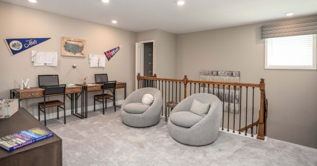 Modern home office with dual desks, cozy gray chairs, and sports decor creating a stylish and functional workspace.