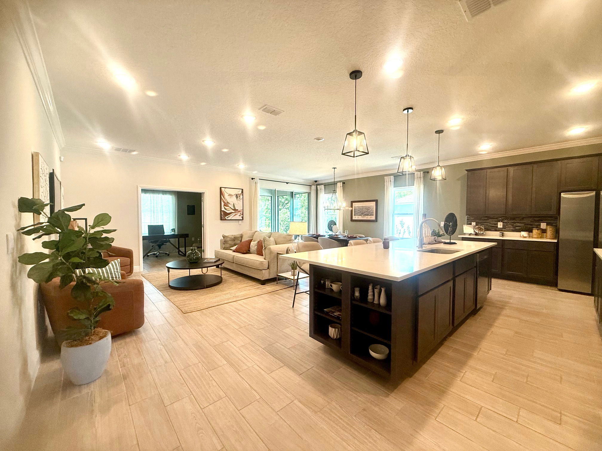 Modern open-concept living room and kitchen with recessed lighting, island counter, and elegant decor.
