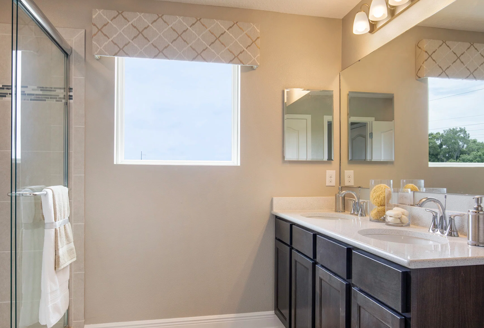 Modern bathroom featuring a double vanity, large mirrors, and a glass shower.