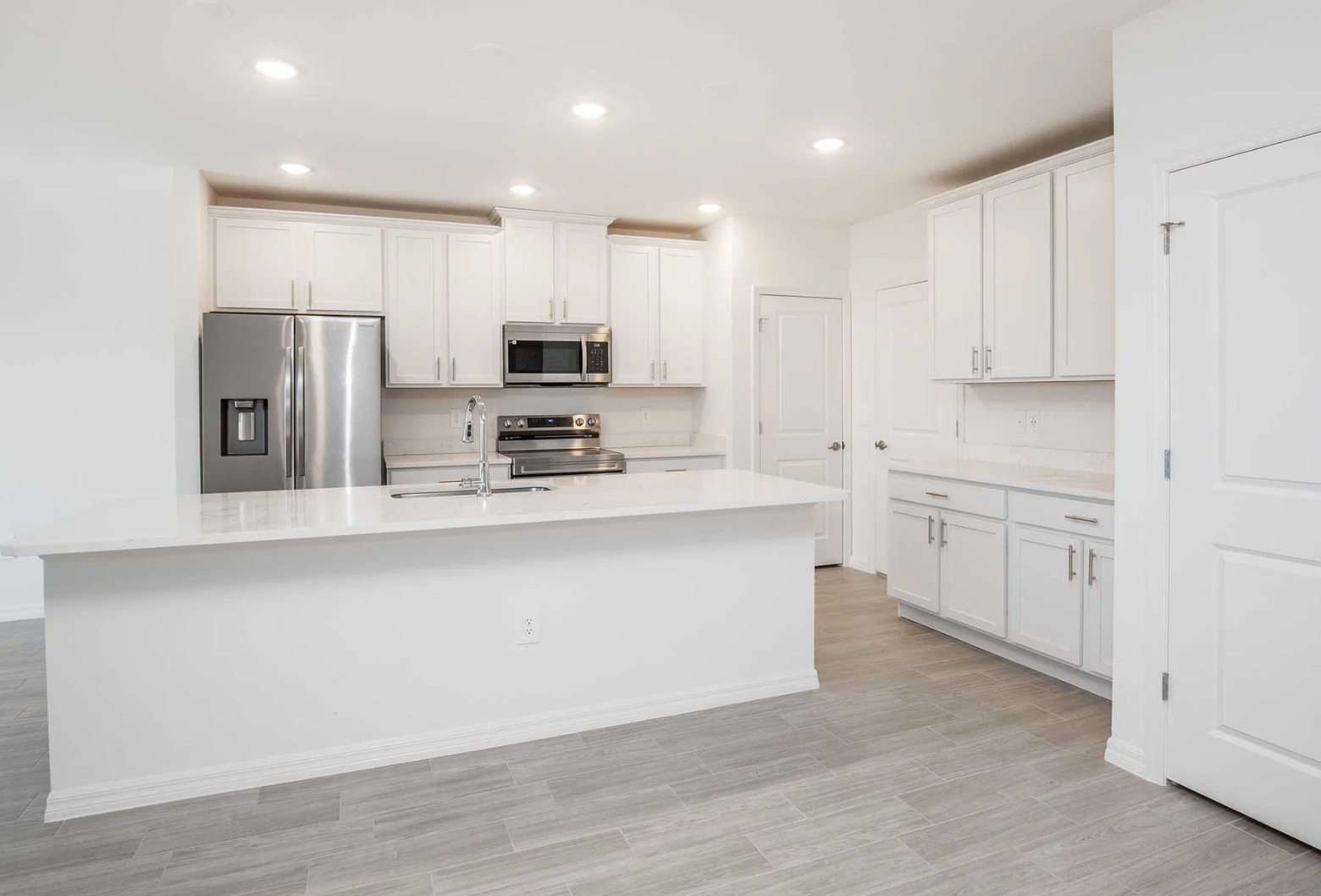 Modern kitchen featuring stainless steel appliances, white cabinetry, and a spacious island with a sleek countertop.