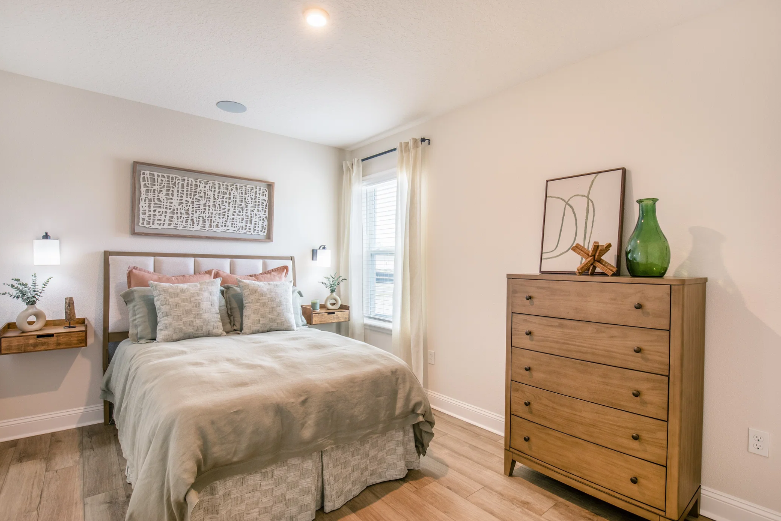 Cozy modern bedroom featuring a neatly made bed, decorative pillows, stylish bedside tables, and elegant wooden furniture.