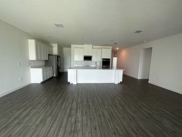 Spacious modern kitchen with white cabinets, a central island, and sleek hardwood flooring.