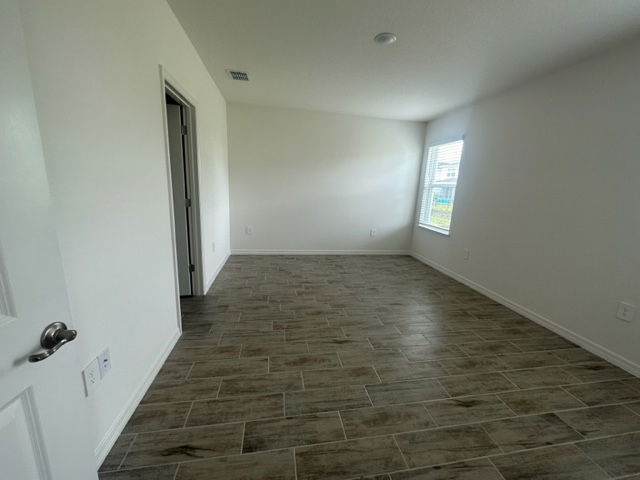 Empty room with light wood-look tile flooring, white walls, and a window allowing natural light.