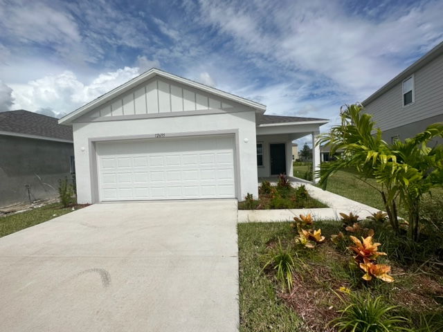 Modern single-story white house with a two-car garage, landscaped front yard, and a clear blue sky backdrop.