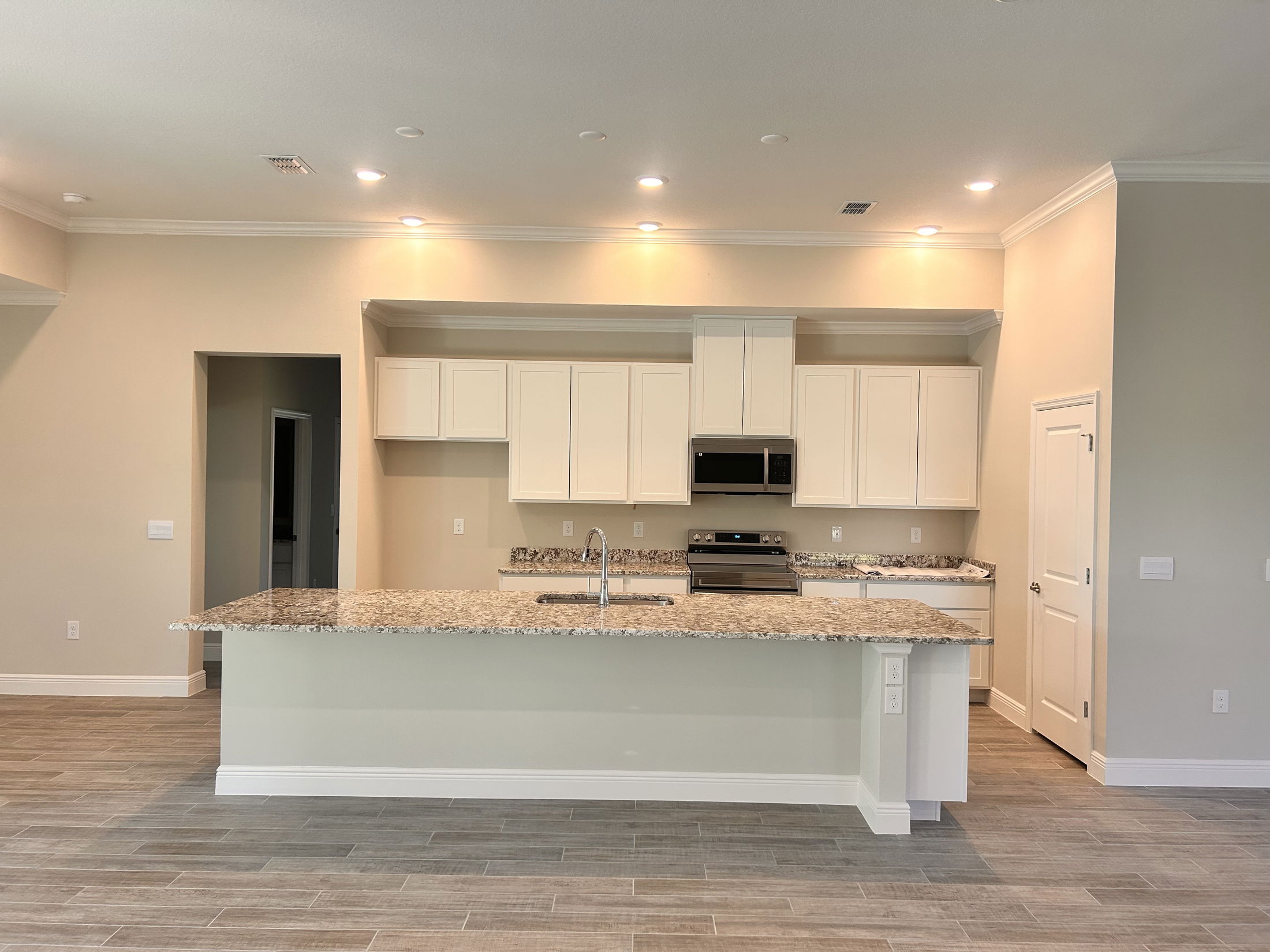 Modern kitchen interior with granite countertops, stainless steel appliances, and white cabinetry.