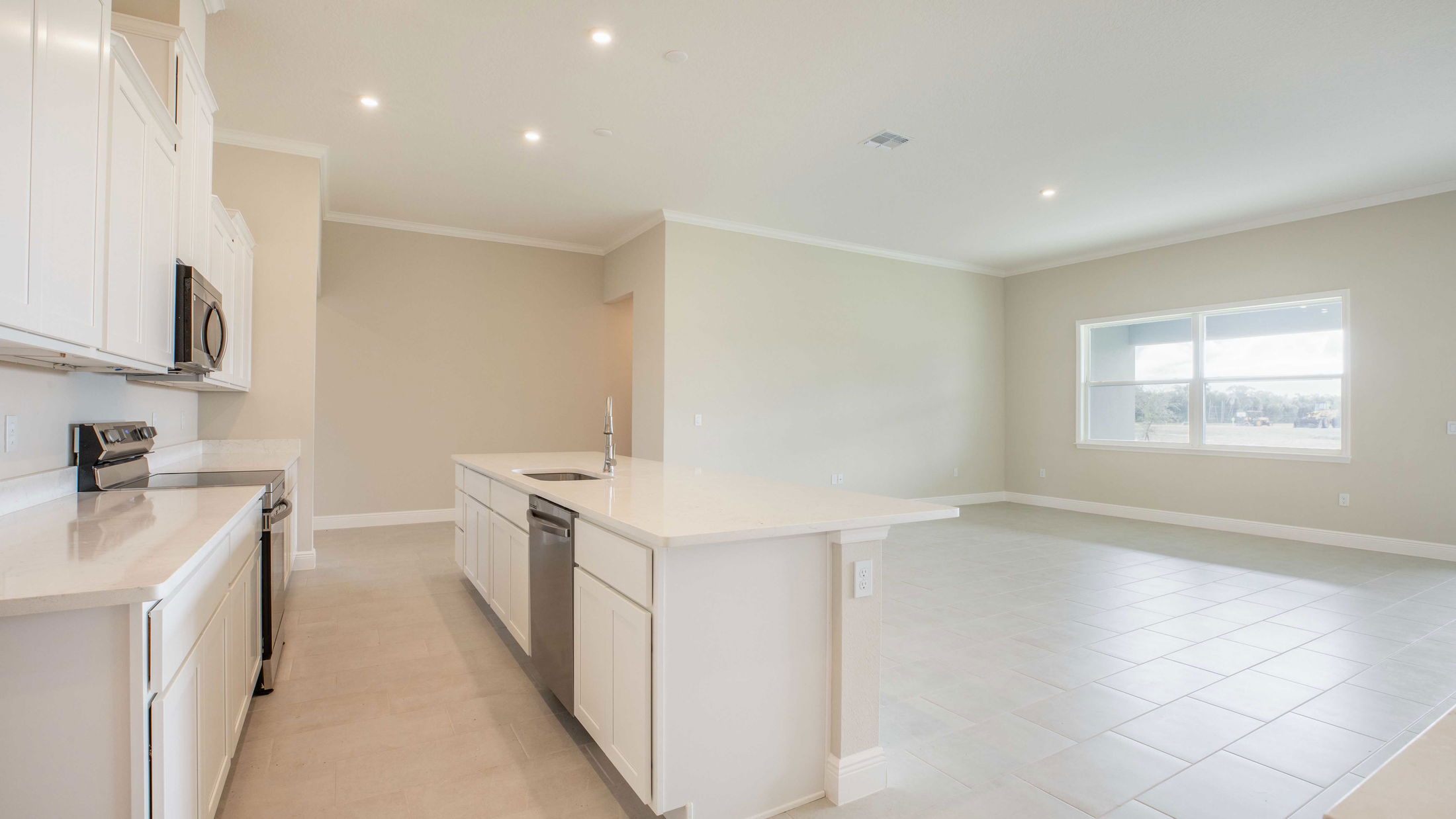 Modern open-concept kitchen with white cabinetry, a center island, and stainless steel appliances in a well-lit space.