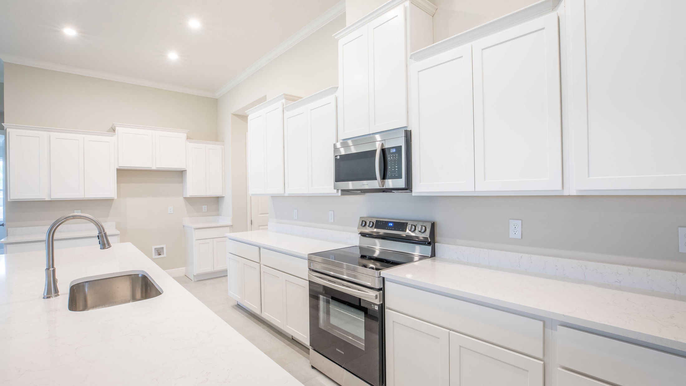 Modern kitchen with white cabinets, stainless steel appliances, and quartz countertops.