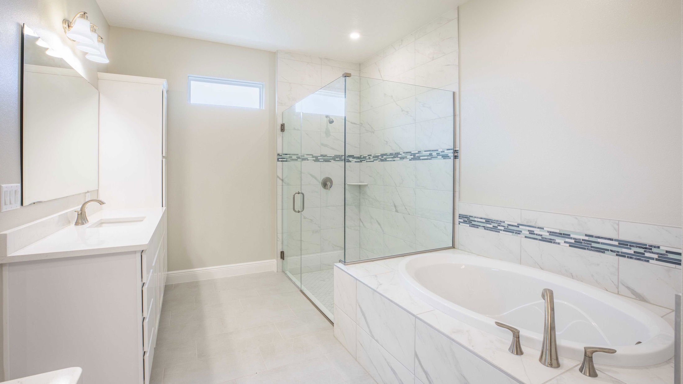 Modern bathroom with a white marble bathtub, glass shower, and sleek vanity.