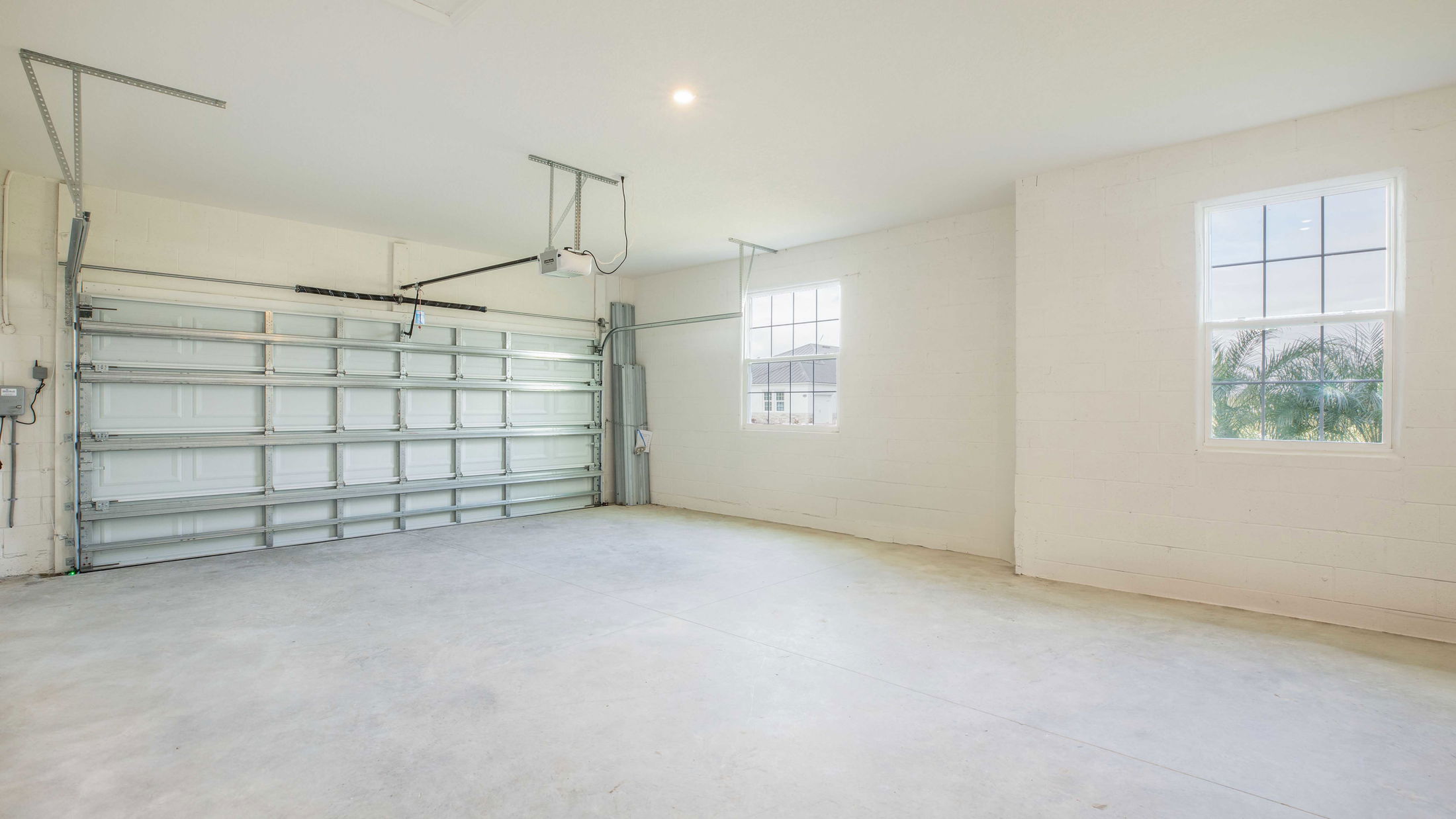 Empty residential garage with white walls, concrete floor, and automatic double door.