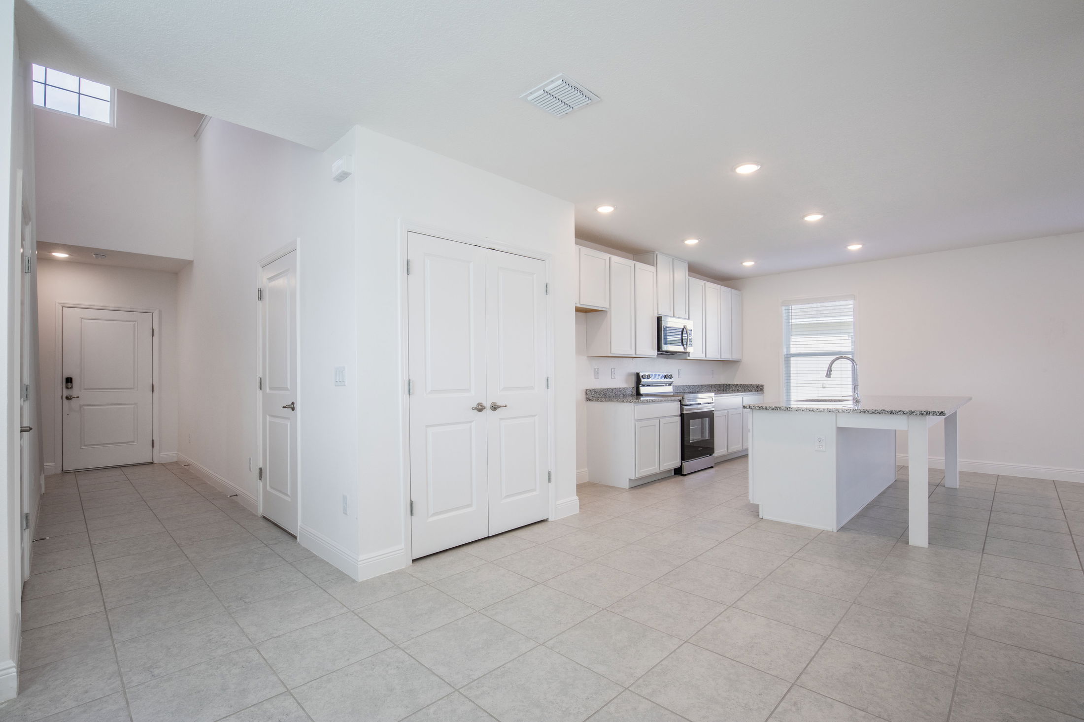 Modern open-concept kitchen featuring white cabinets, stainless steel appliances, and a spacious island with a sink, in a bright and airy interior.