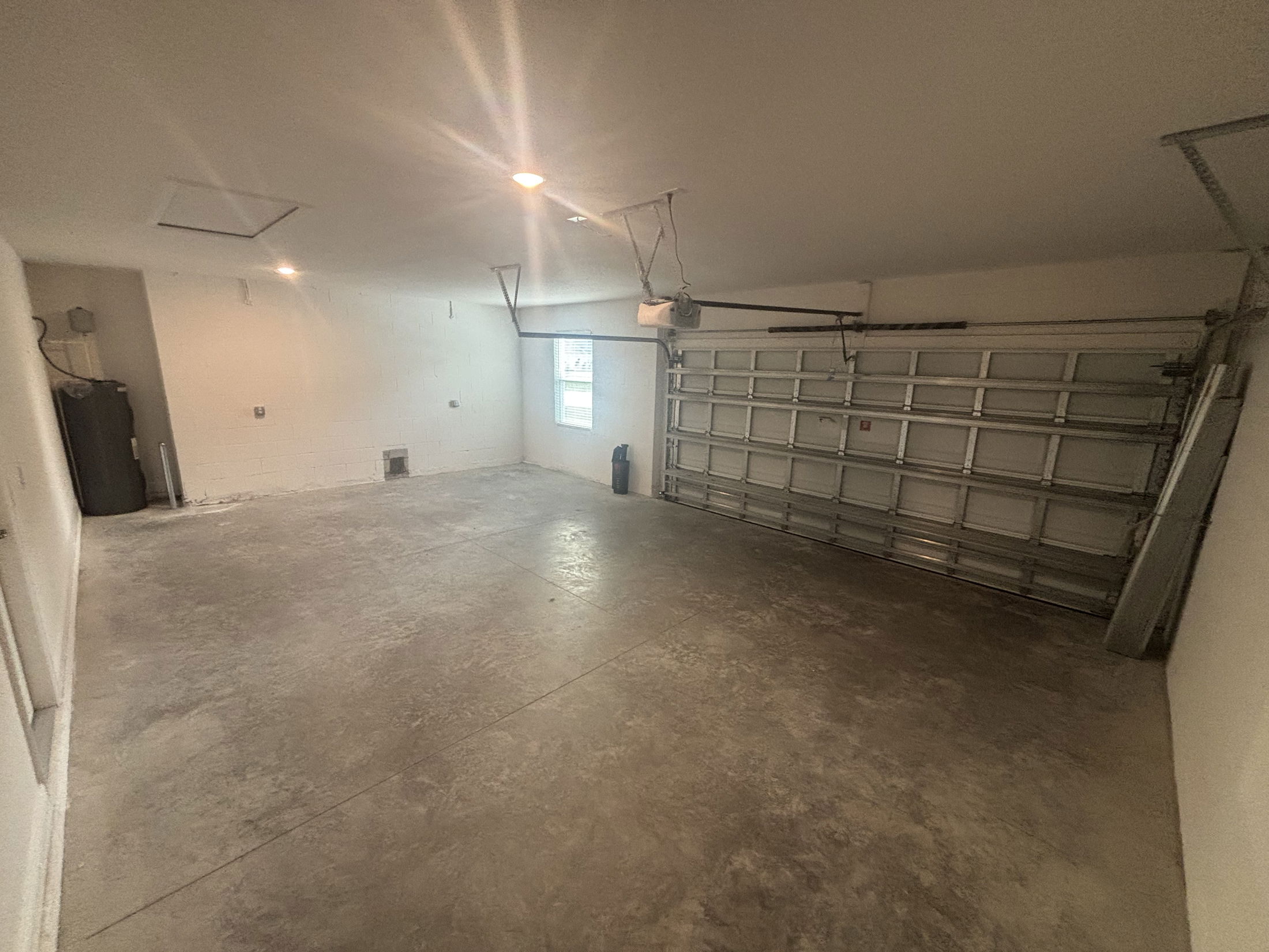 Empty residential garage with concrete floor, white walls, and a closed metal garage door.