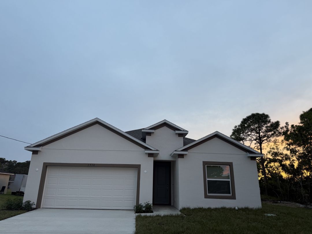 Modern single-story home with a two-car garage and a sunset sky backdrop.