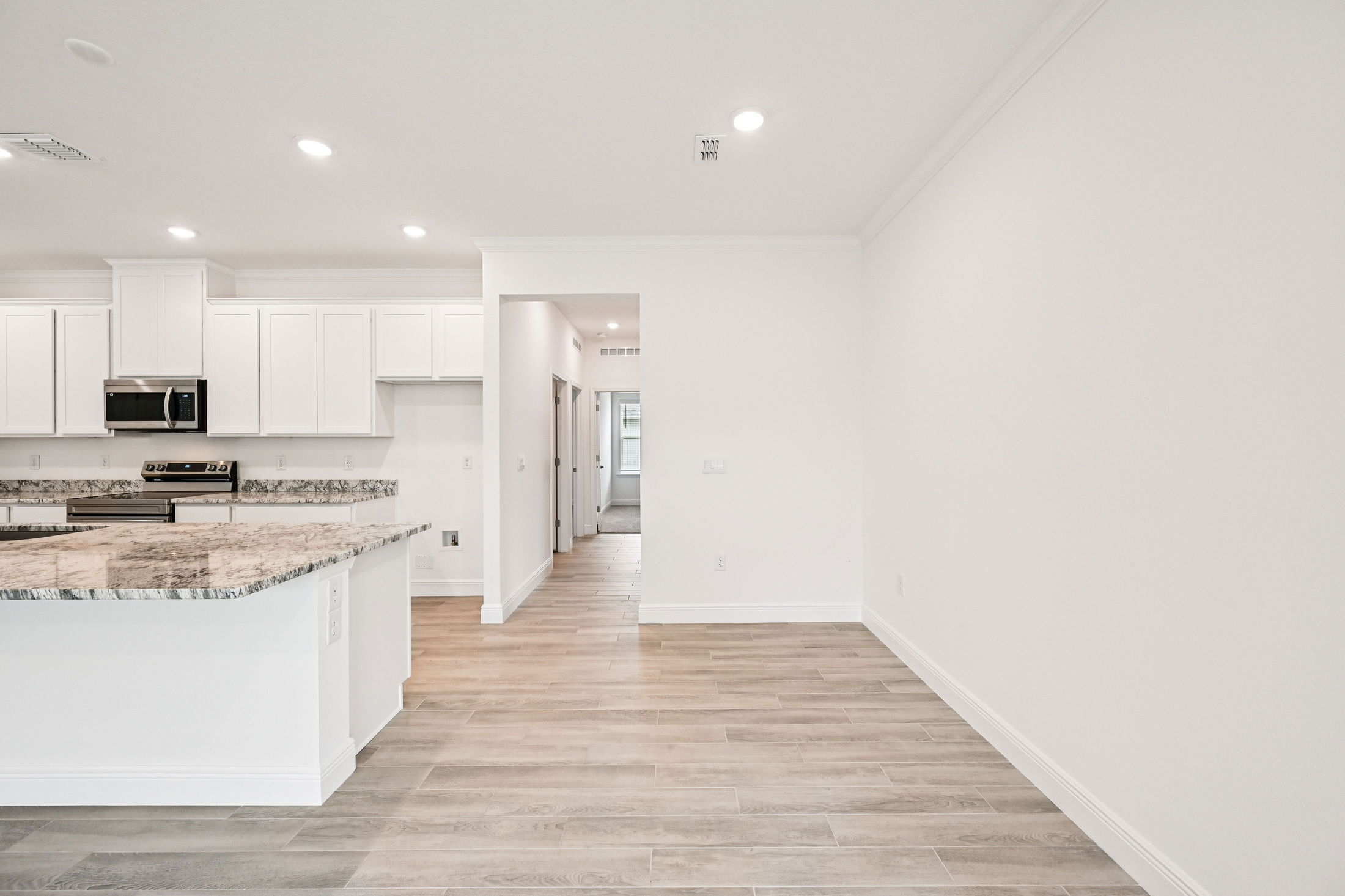 Modern kitchen interior featuring granite countertops, stainless steel appliances, and light wood flooring in an open layout design.