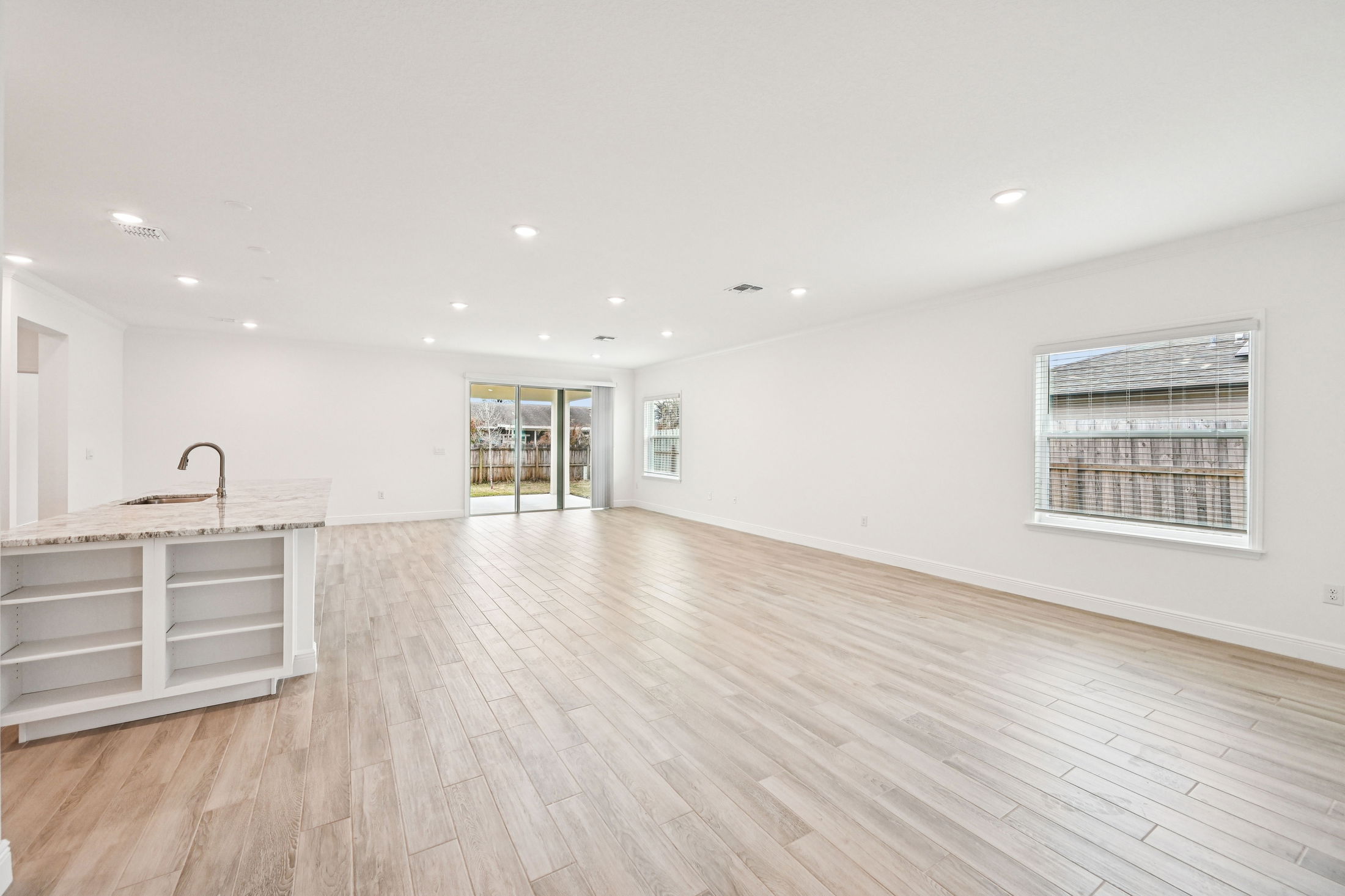 Bright and spacious modern living room with hardwood floors and sliding glass doors leading to a backyard.