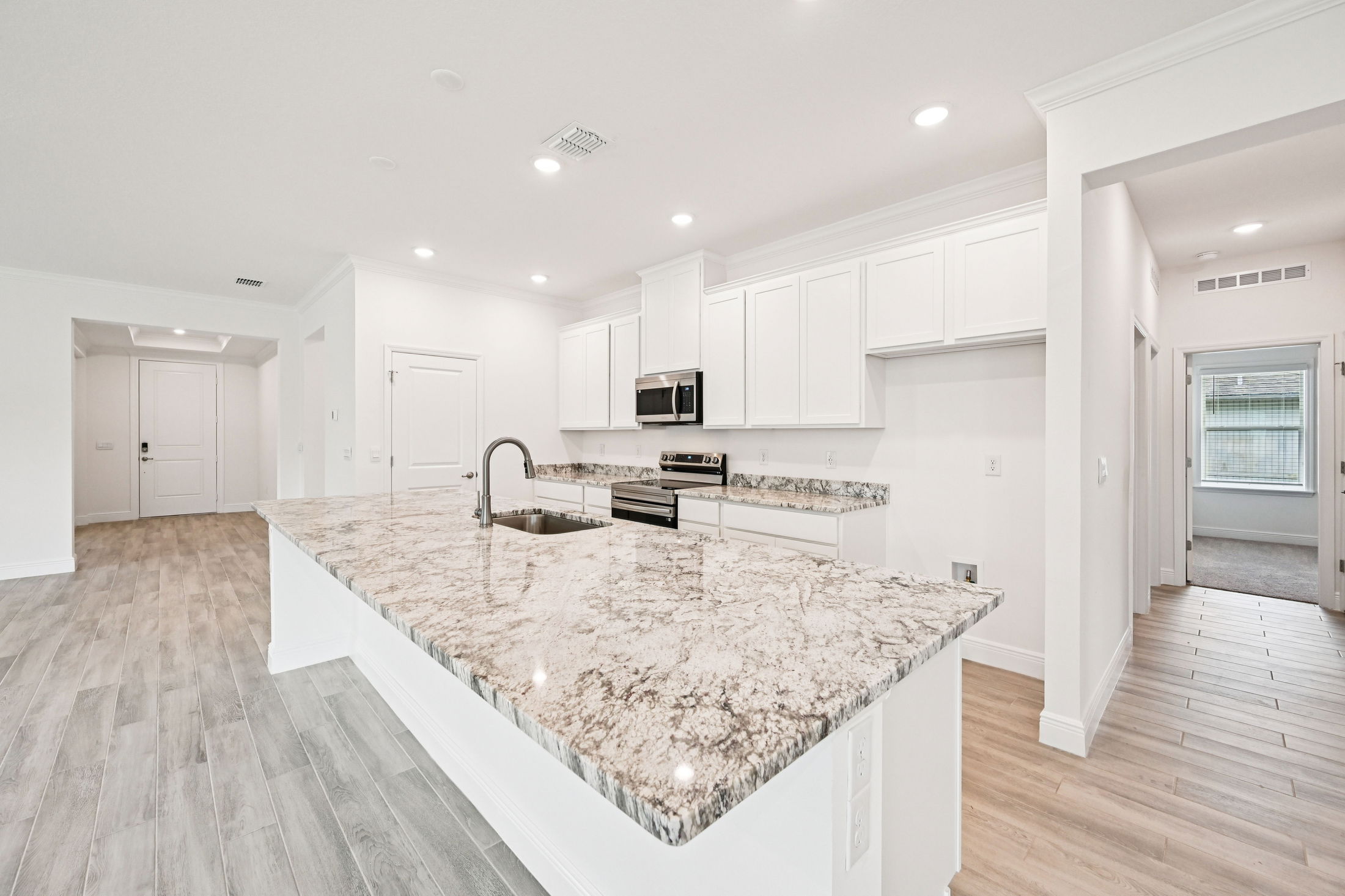 Modern kitchen interior featuring a spacious granite countertop and white cabinetry.