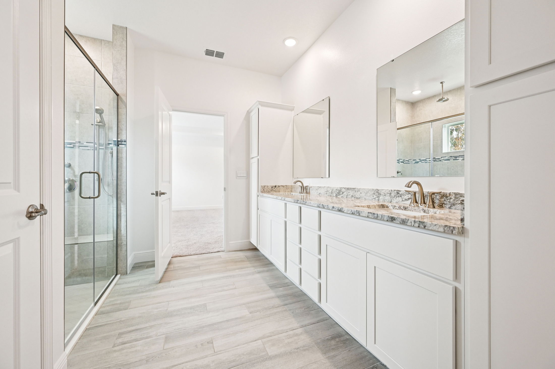 Modern bathroom design featuring a double vanity with granite countertop, large mirrors, glass shower, and neutral color palette.