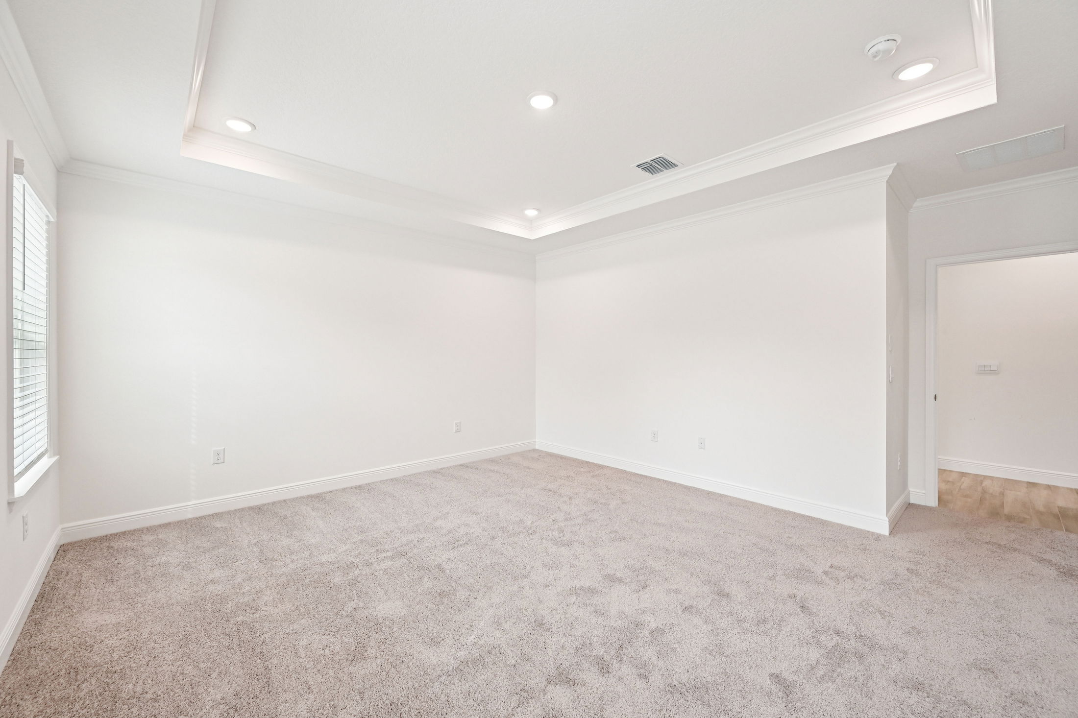 Spacious and bright living room featuring plush carpet and modern crown molding in a newly constructed home.