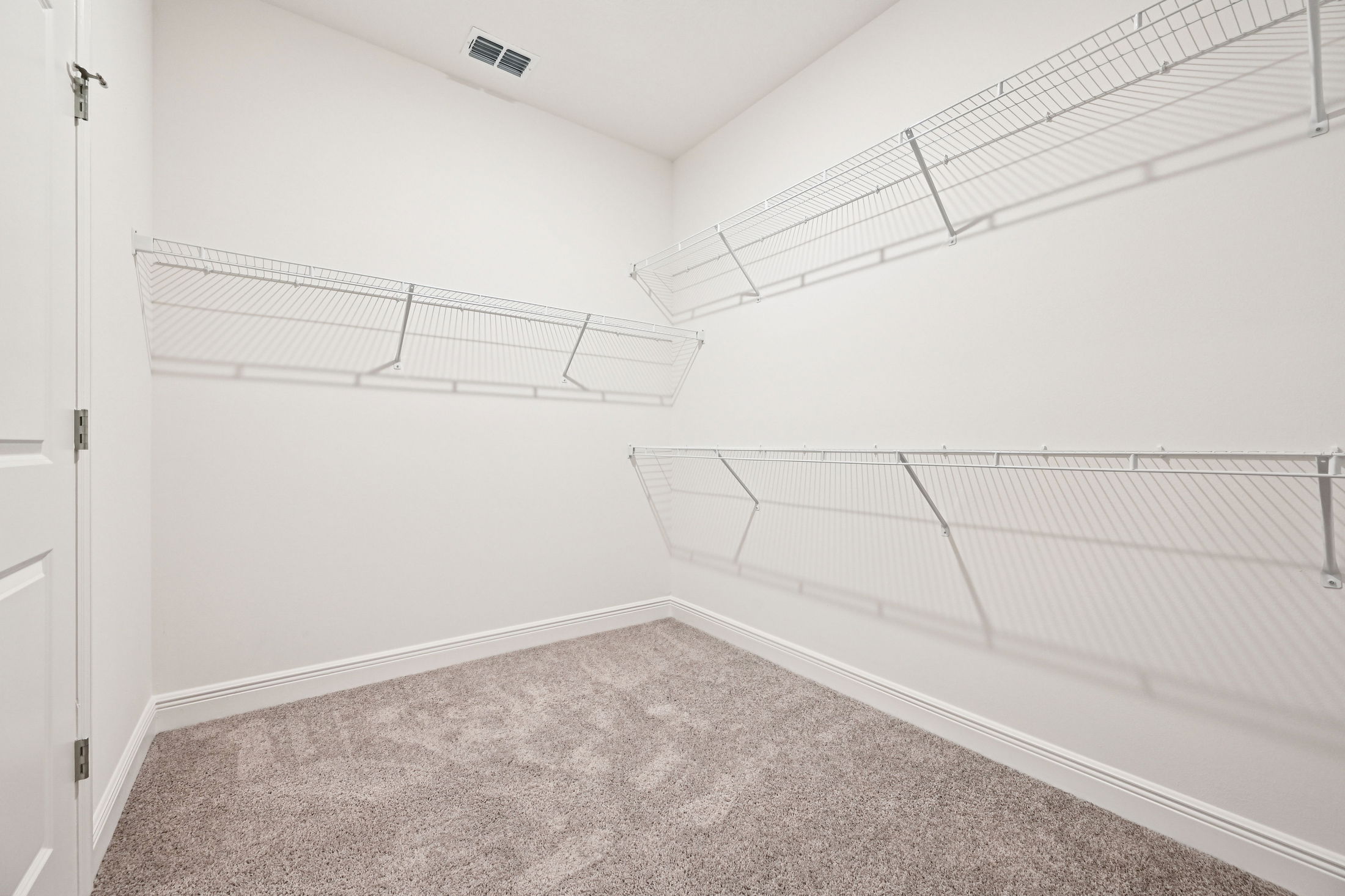 A spacious empty closet featuring wire shelving and plush carpet flooring, perfect for organization and storage.