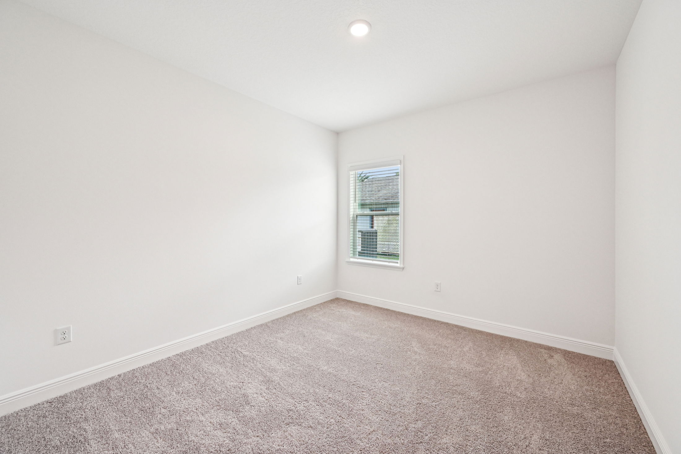 Empty bedroom with carpet flooring and a window allowing natural light to enter.
