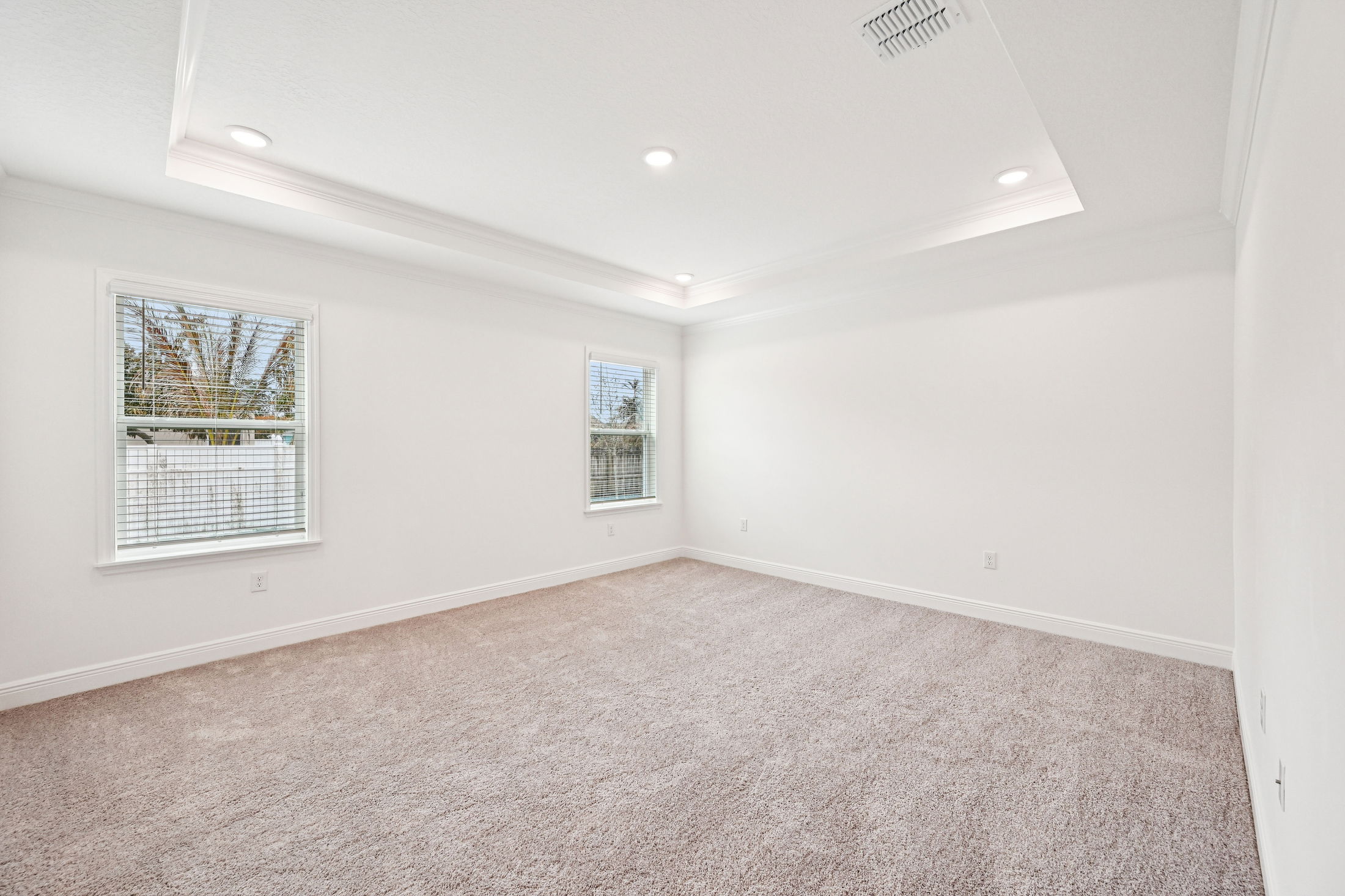 Bright and spacious modern bedroom with large windows and plush carpeting, ideal for a comfortable living space.