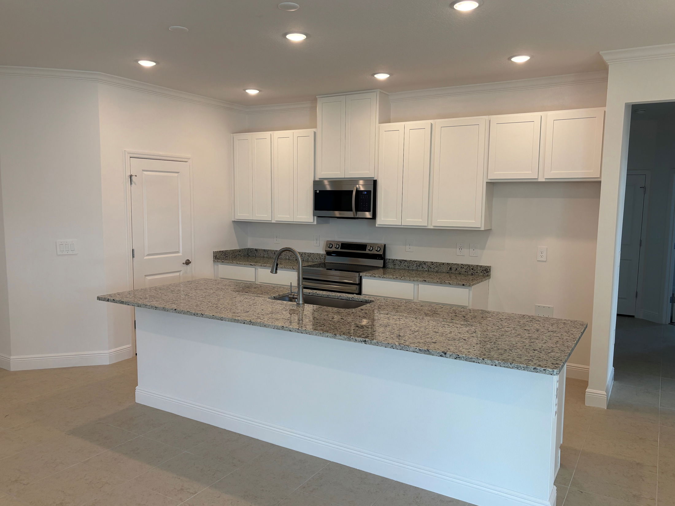 Modern kitchen with white cabinets, granite countertops, and stainless steel appliances.