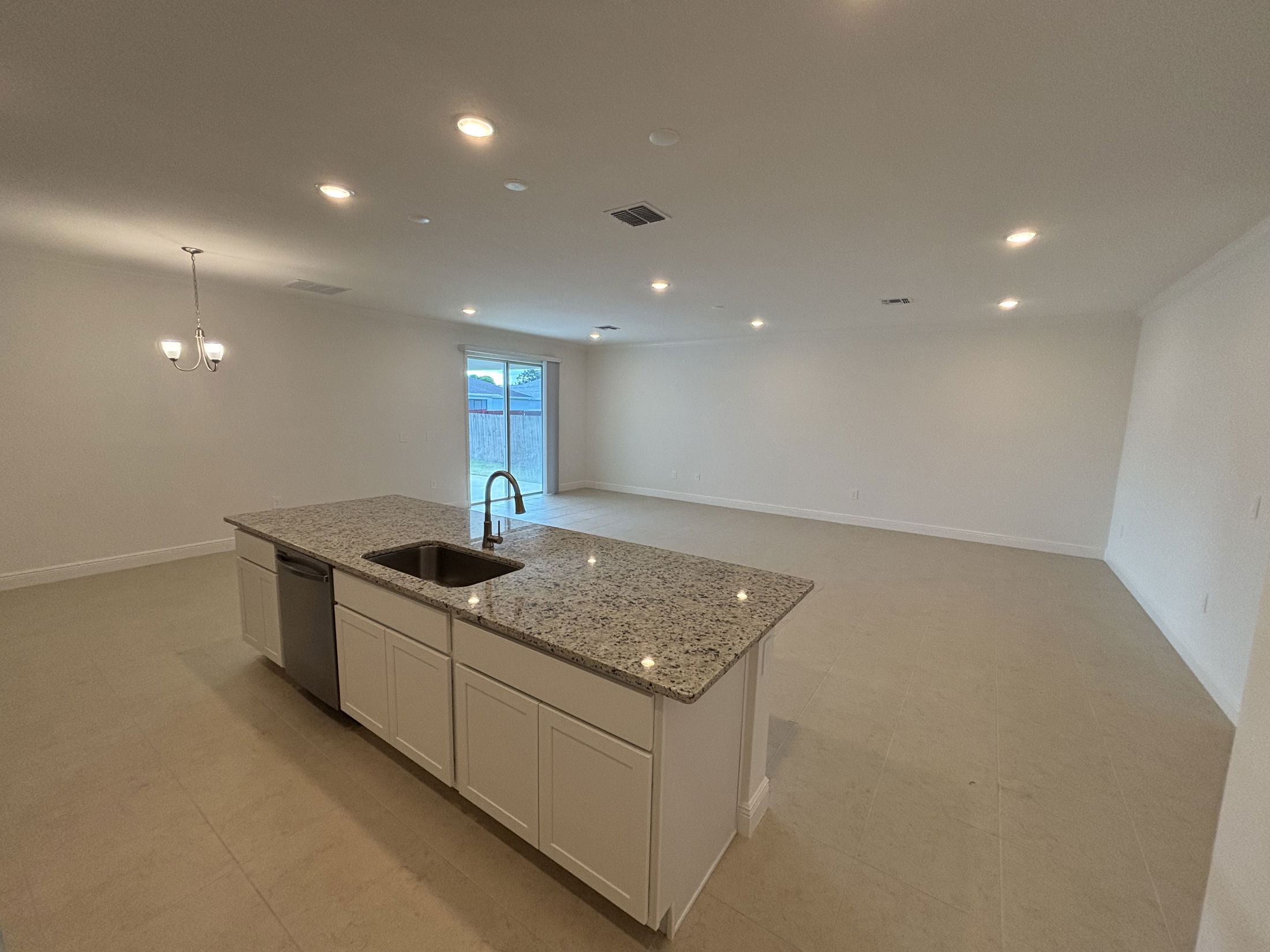 Modern open-concept kitchen and living area with granite countertop island and recessed lighting.