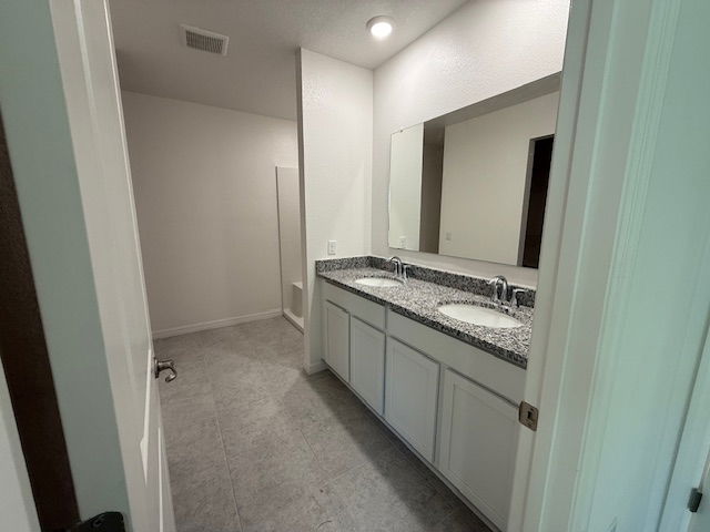 Modern bathroom with dual sinks, granite countertops, large mirror, and a walk-in shower.