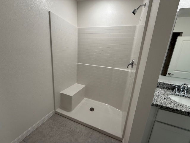 Modern bathroom with a walk-in shower featuring white tiled walls, a built-in bench, and adjacent granite countertop sink area.