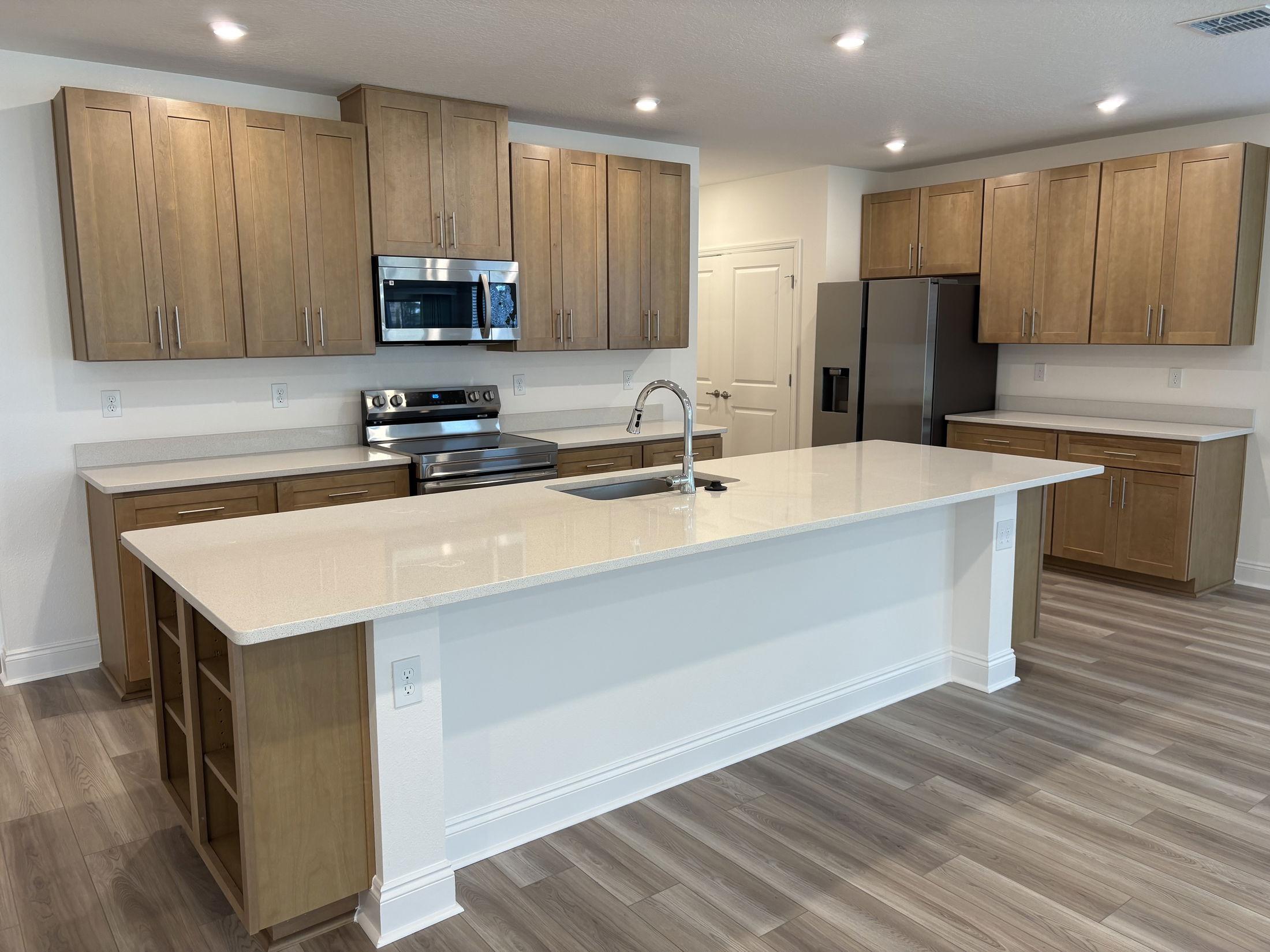 Modern kitchen featuring sleek wooden cabinets, stainless steel appliances, and a spacious island with a quartz countertop.
