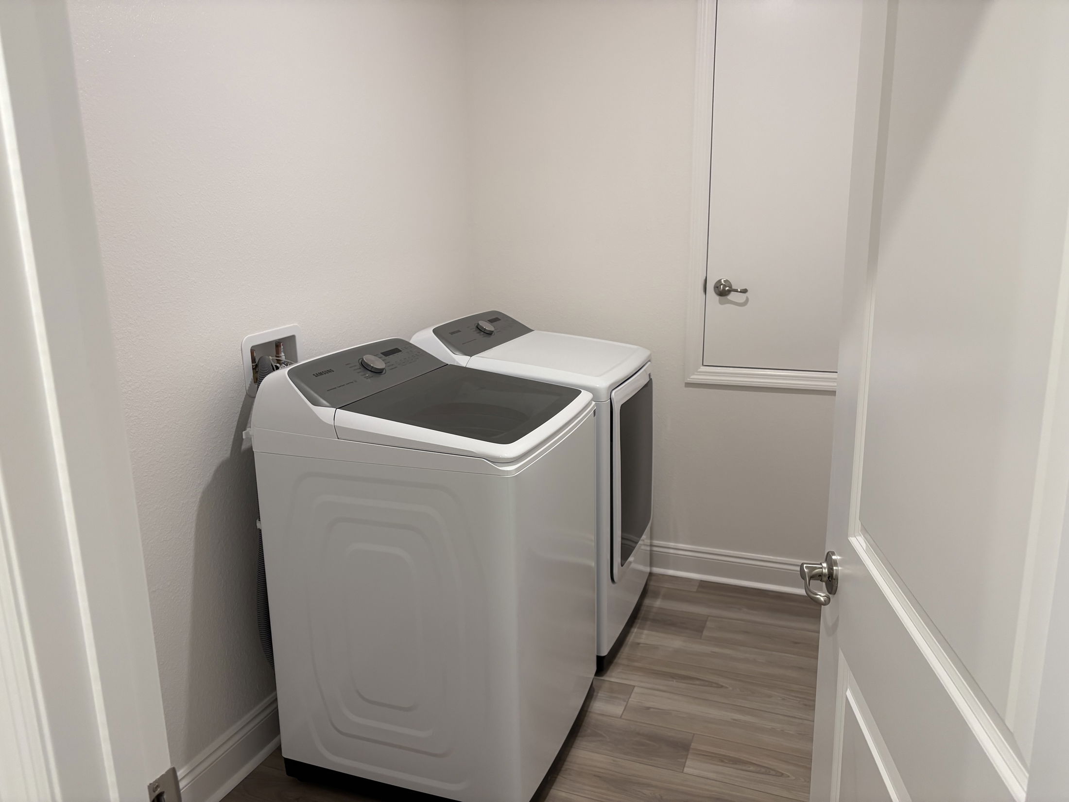 A modern laundry room featuring two white washing machines side by side against a neutral wall.