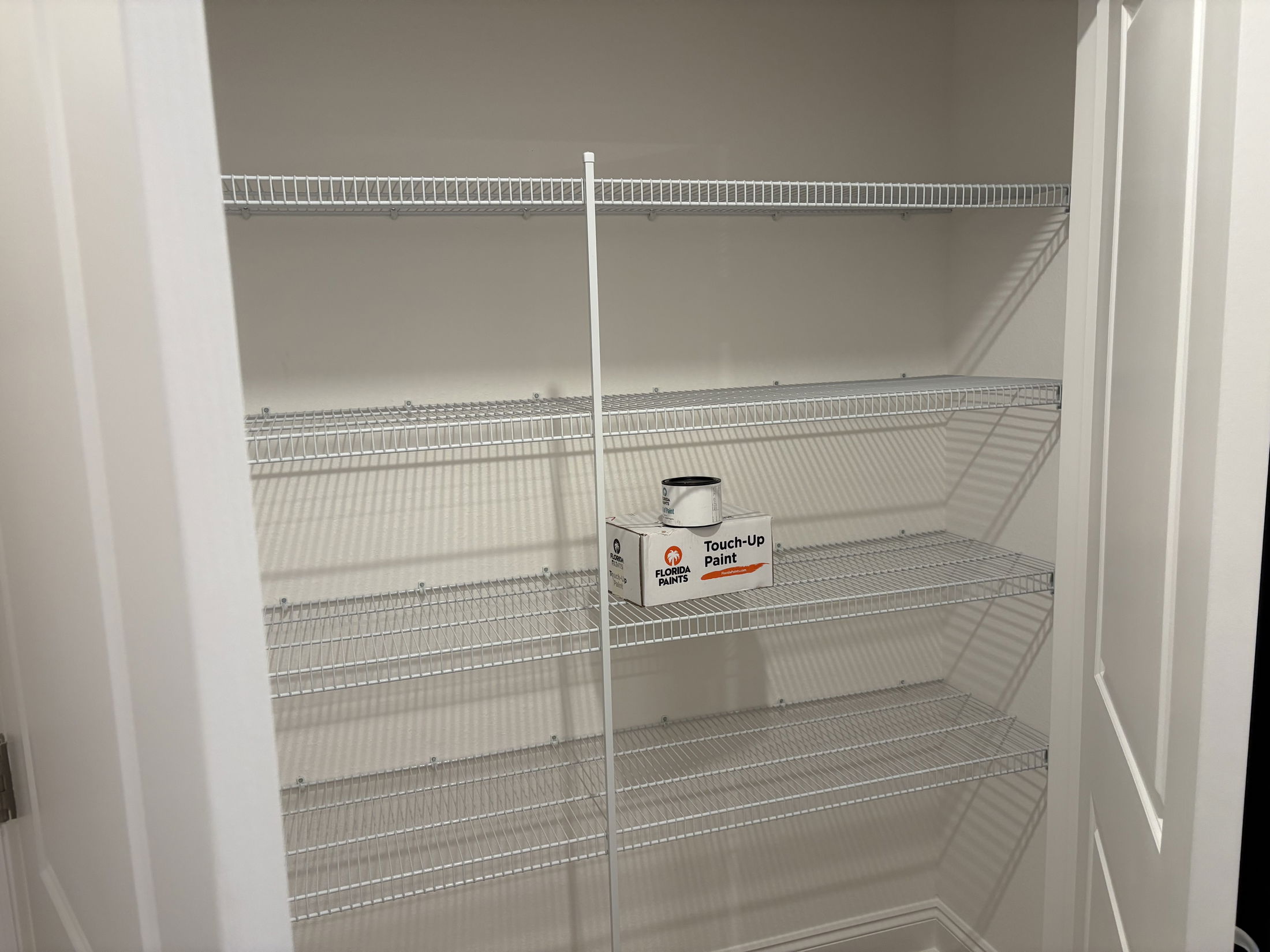 Empty closet shelves with a can of touch-up paint on the bottom shelf.