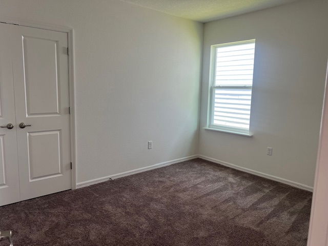 Small empty bedroom with white walls, a carpeted floor, a window with blinds, and a closed double door closet.