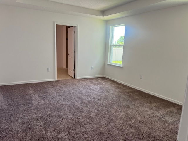 Bright, carpeted empty room with a window and open doorway leading to another space.