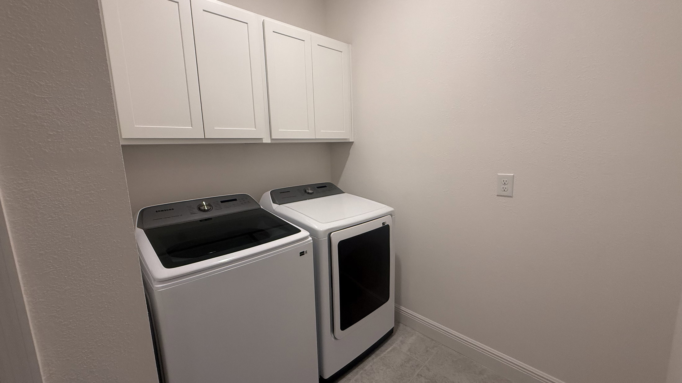 A laundry room featuring a washer and dryer with white cabinets above.