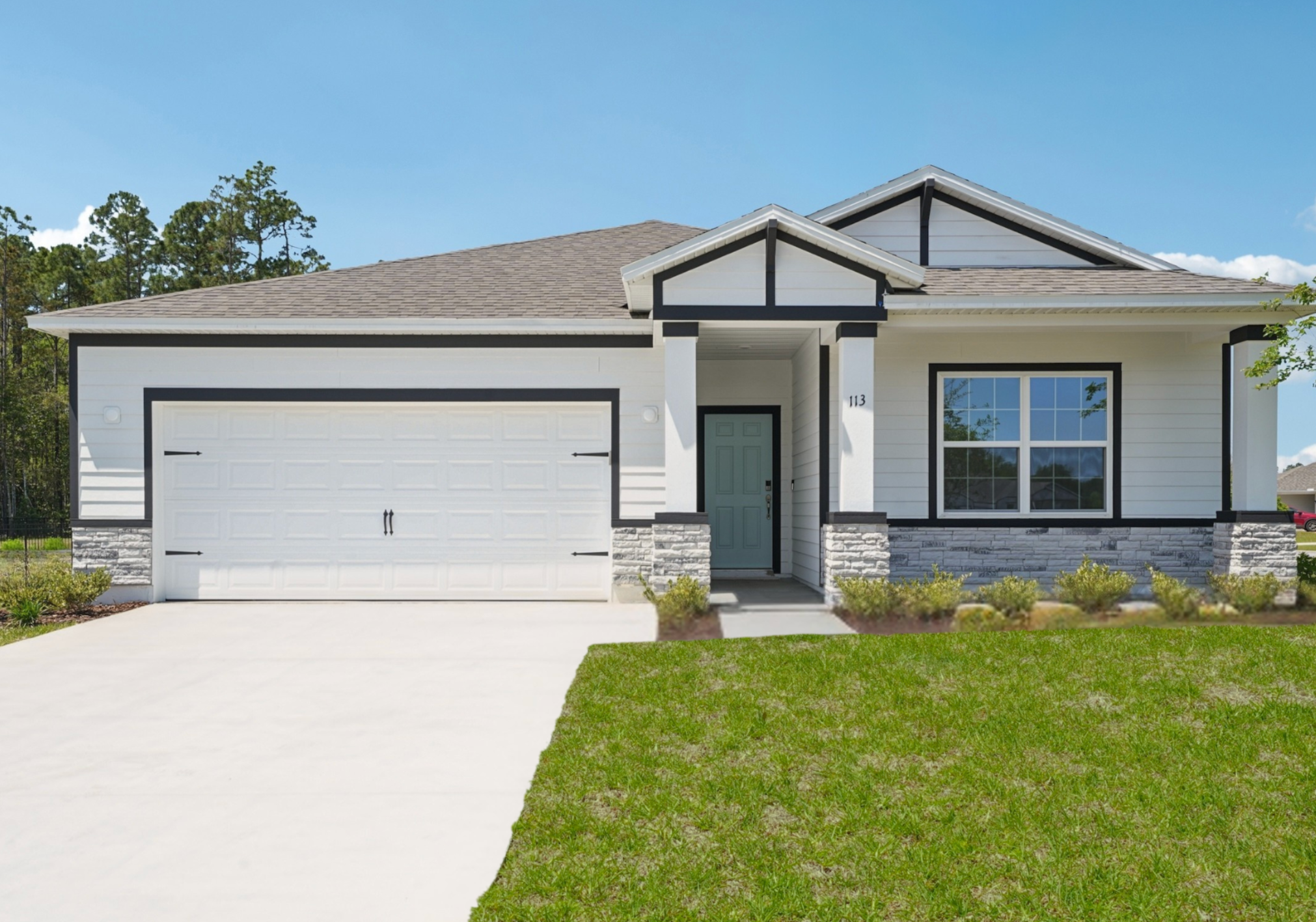A modern single-story house with a gray roof, light-colored siding, and a stone-accented facade, featuring a garage and landscaped front yard.