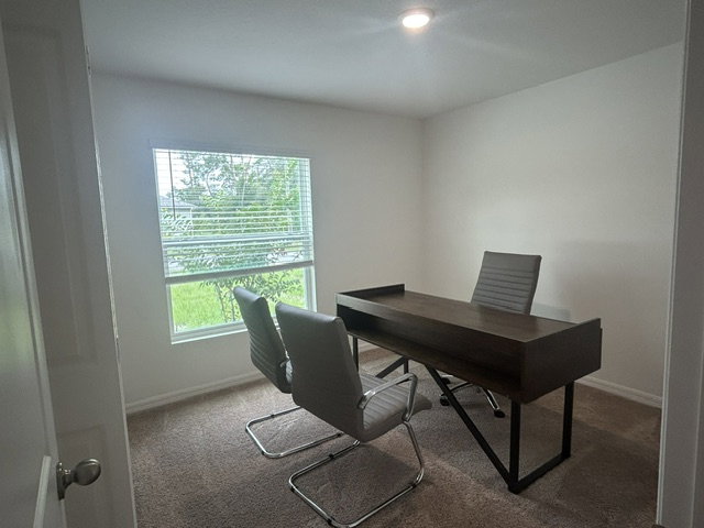 A minimalist office featuring a wooden desk, two modern chairs, and a window with natural light.