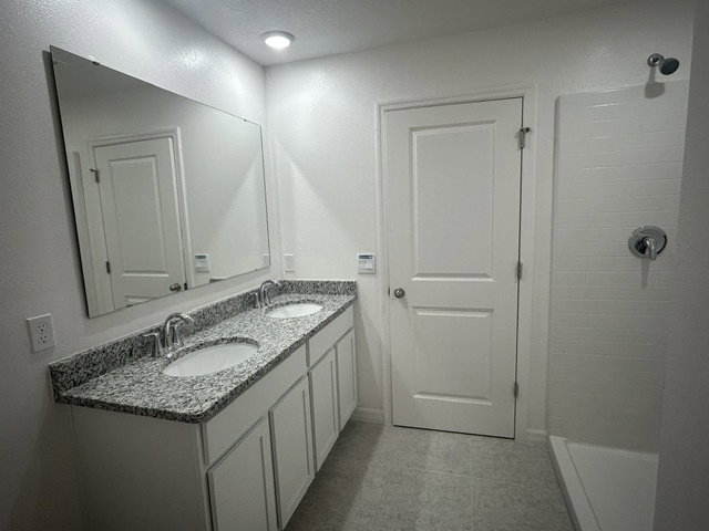 Bright, modern bathroom with a double vanity, large mirror, and a shower stall.