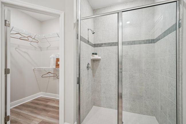 Modern bathroom featuring a glass-enclosed shower and a walk-in closet with hanging space.