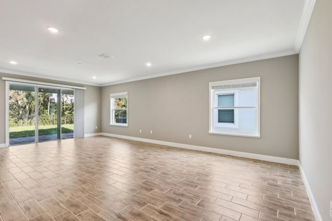 Spacious room with wooden flooring, large windows, and sliding glass doors leading to an outdoor area.